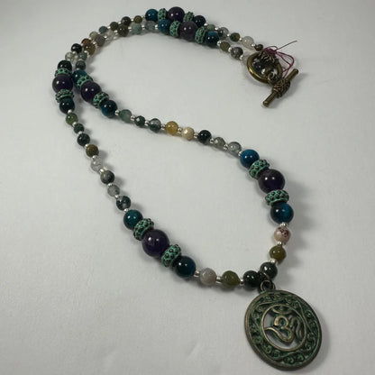 Bronze patina Om pendant necklace with dark green and purple beads
