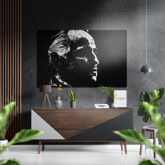 Black and white portrait of a man displayed above a wooden dresser in a modern interior setting with plants and pendant lighting.
