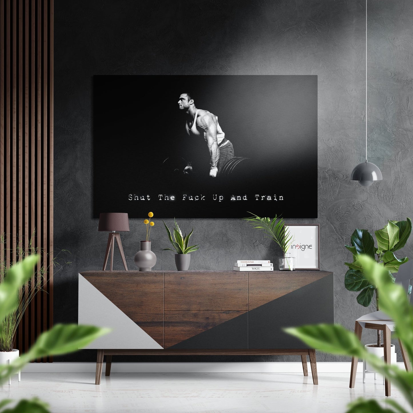 Black and white motivational wall art featuring a muscular man lifting dumbbells with text "Shut The Fuck Up and Train" displayed above a wooden credenza in a modern interior.