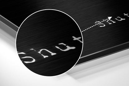 Close-up detail of brushed aluminum train wall art showing embossed text and directional arrow on dark textured surface.