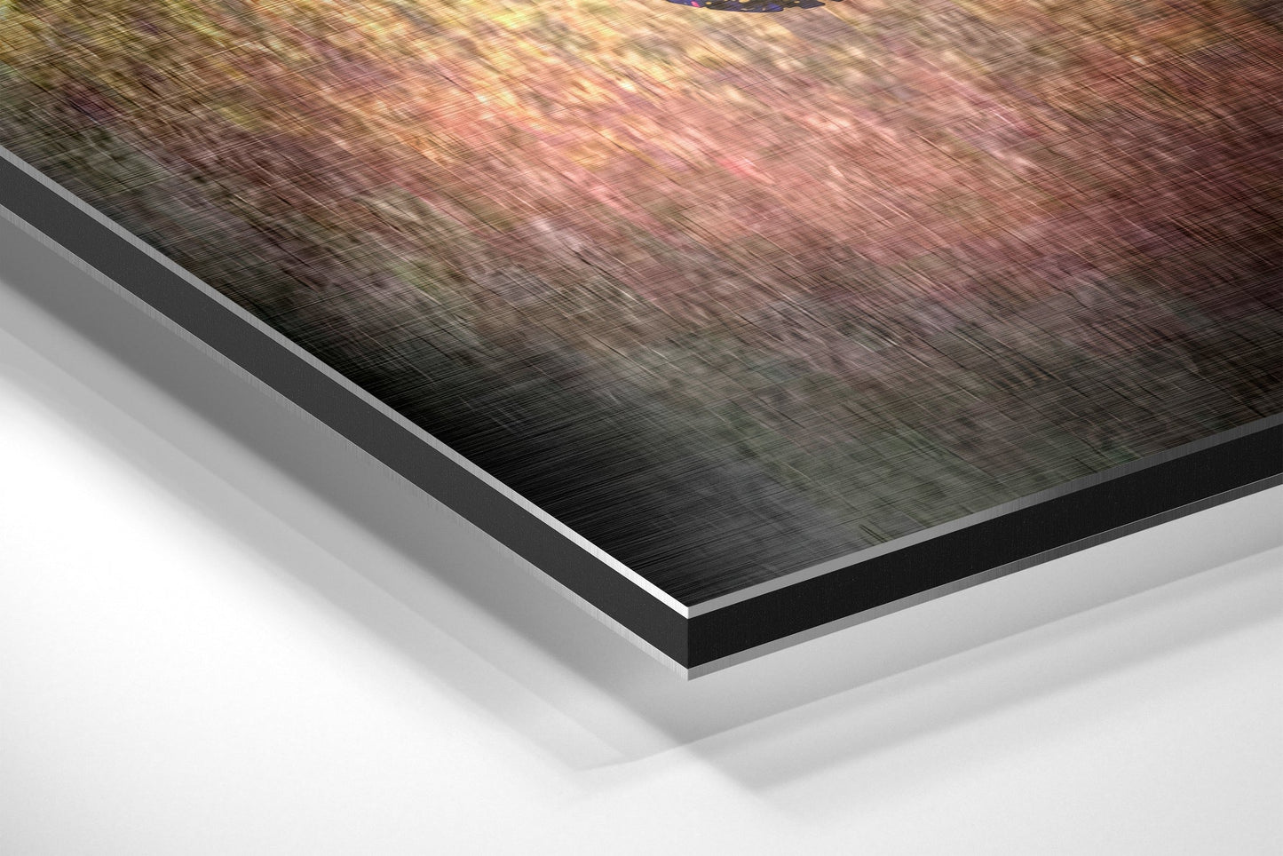Close-up angled view of layered Dibond wall art showing brushed aluminum surface with pink and gold tones and white backing layers.