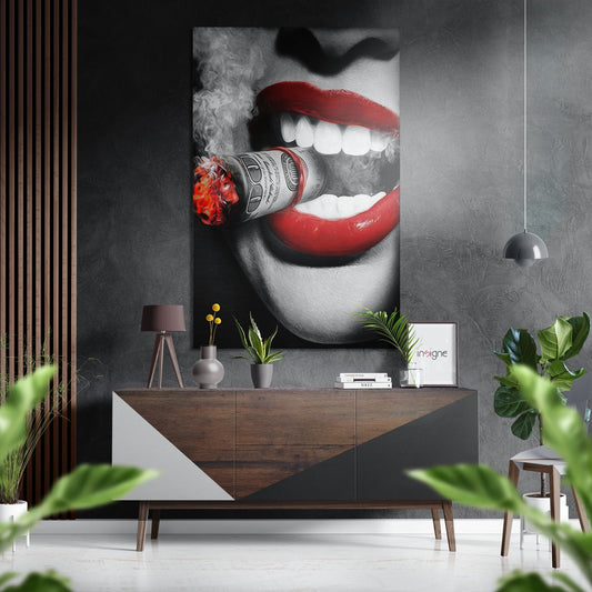 Modern interior scene featuring black and white portrait with red lips holding flaming money roll mounted above wooden dresser with plants and accessories.