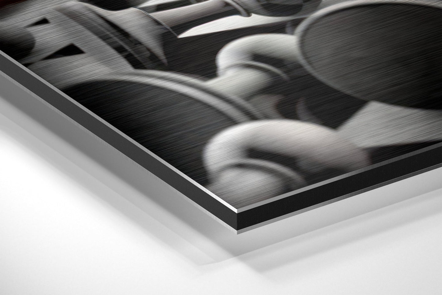 Close-up angled view of brushed aluminium Dibond wall art showing layered edge and textured black and white photograph surface.