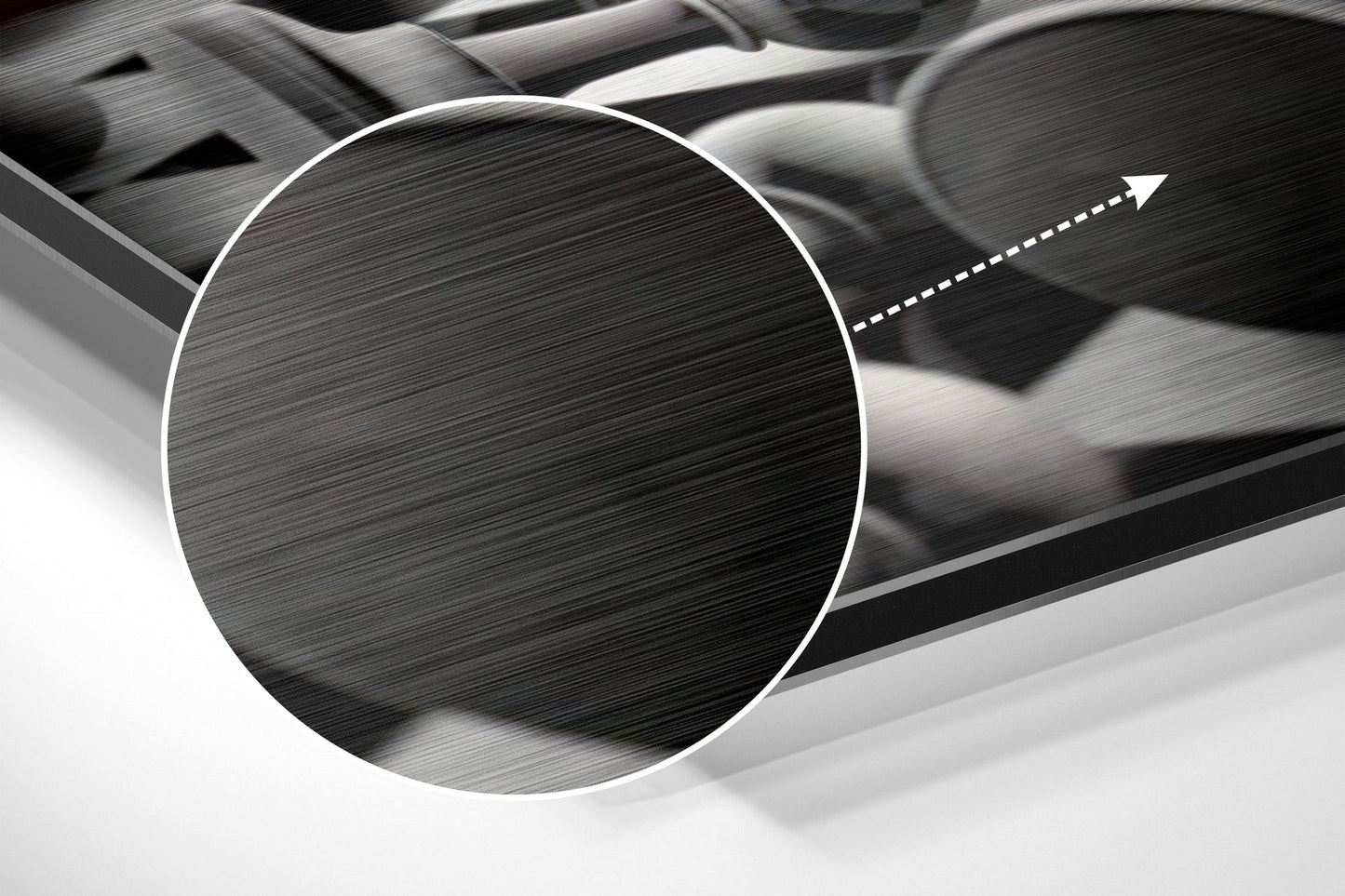 Close-up detail of brushed aluminium surface with horizontal line texture and white circular frame with directional arrow overlay.