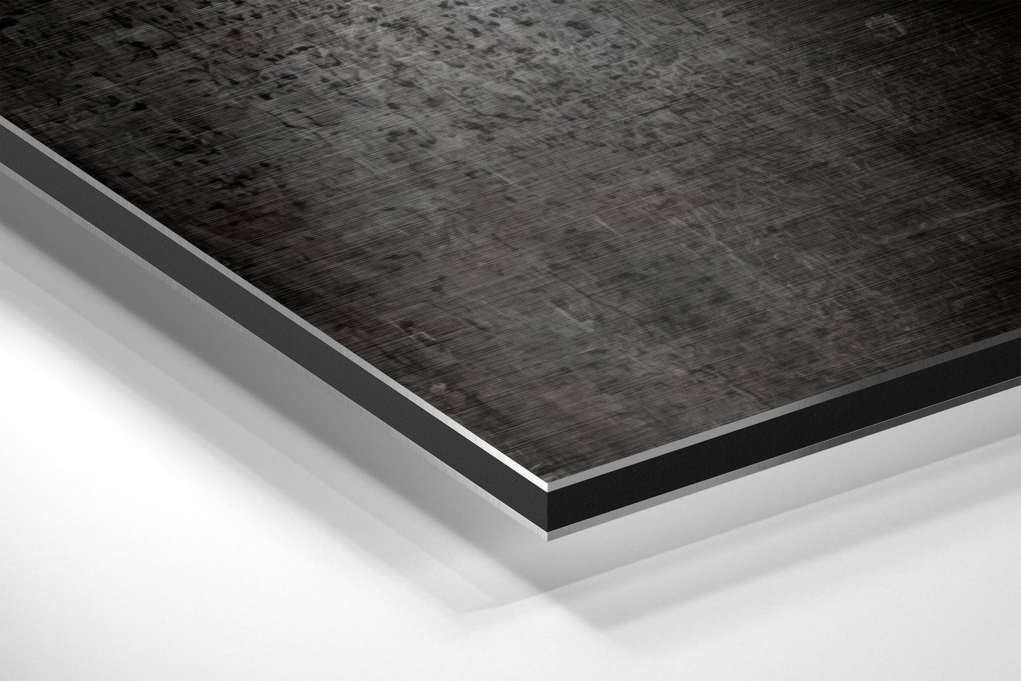 Close-up angled view of layered Dibond panel showing brushed black aluminum top surface with white base layer beneath.