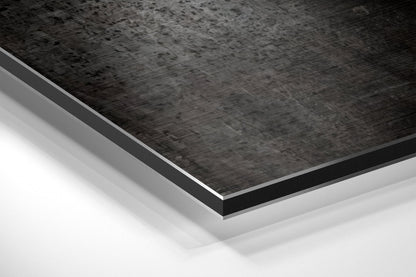 Close-up angled view of layered Dibond panel showing brushed black aluminum top surface with white base layer beneath.