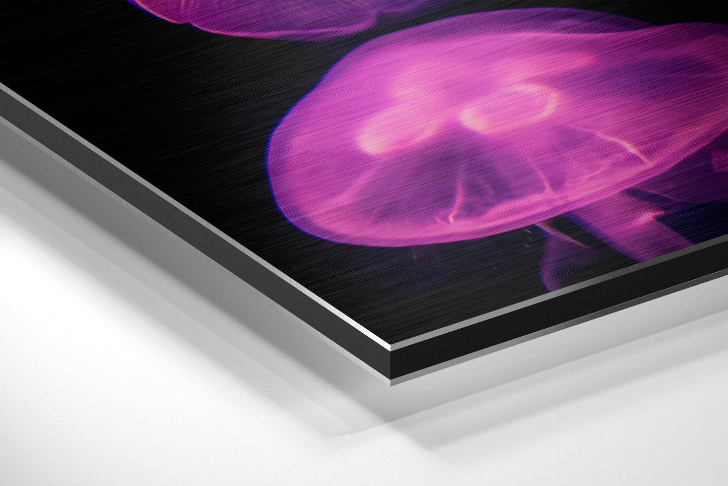 Angled close-up of layered brushed aluminum and black dibond sheet showing vibrant magenta thermal or heat image printed on surface.