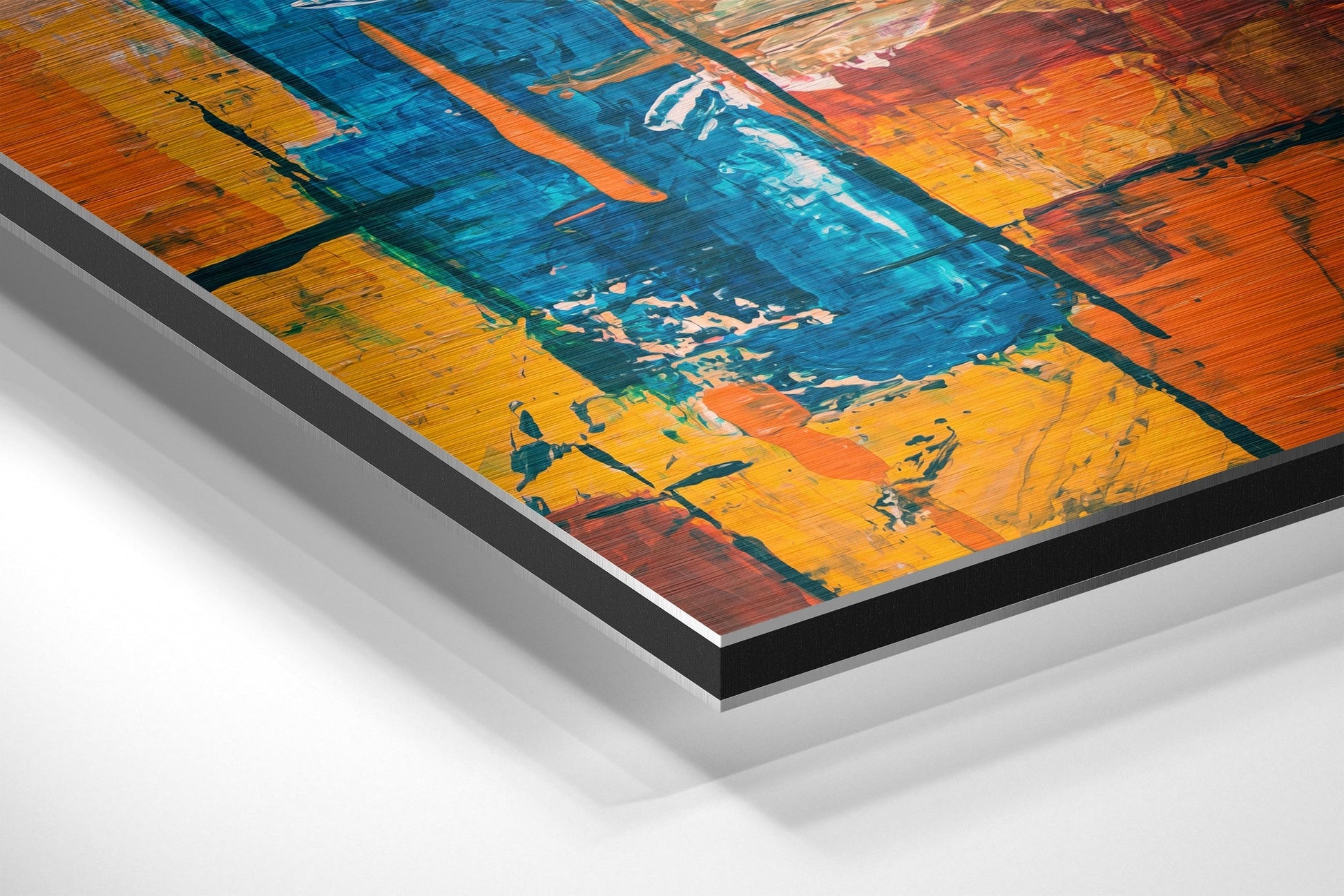 Close-up angled view of brushed aluminum Dibond wall art showing layered edges with vibrant blue, orange, and yellow abstract color blocks.
