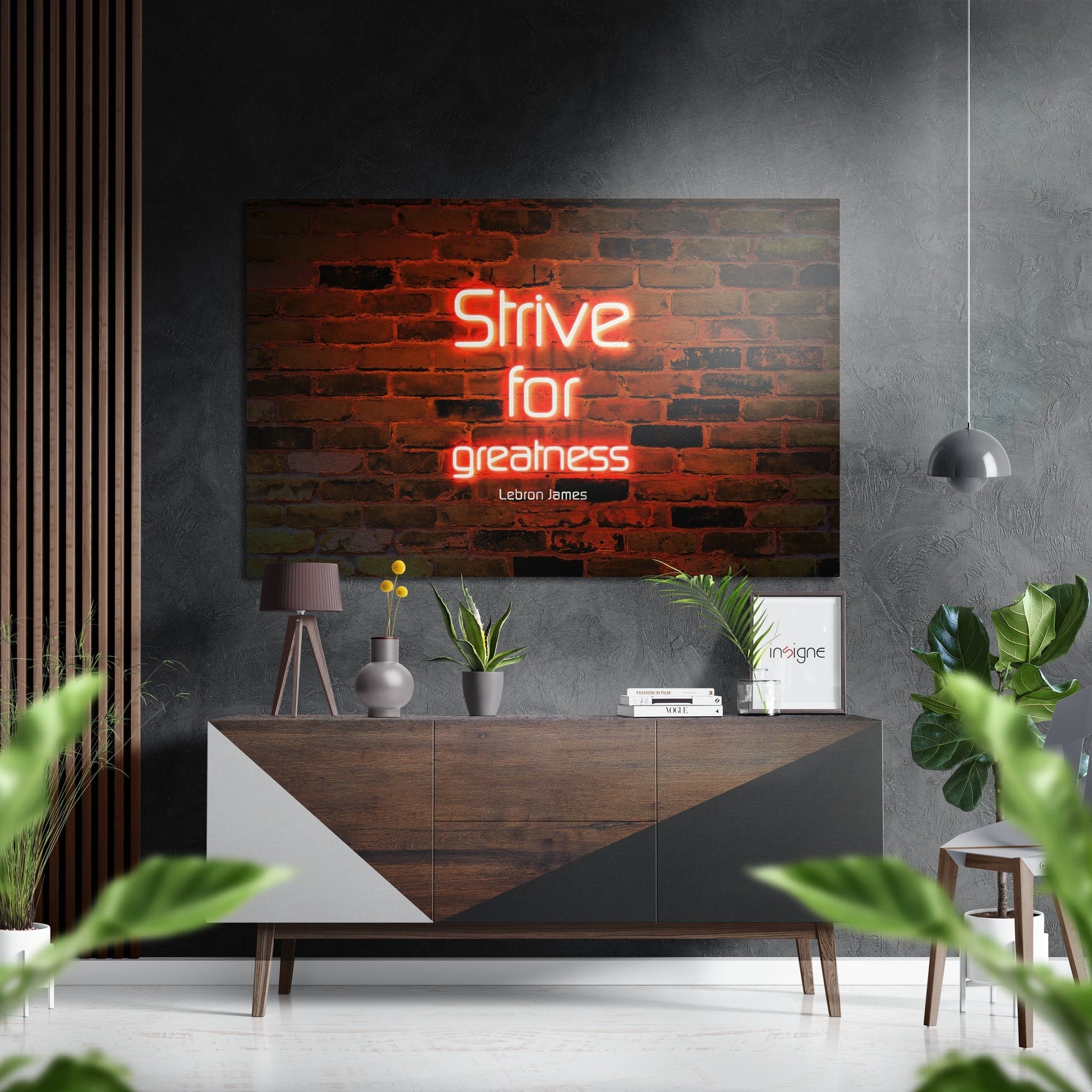 Neon red motivational quote "Strive for greatness" by LeBron James displayed on brushed aluminum above wooden console in modern interior setting.