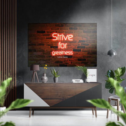 Neon red motivational quote "Strive for greatness" by LeBron James displayed on brushed aluminum above wooden console in modern interior setting.
