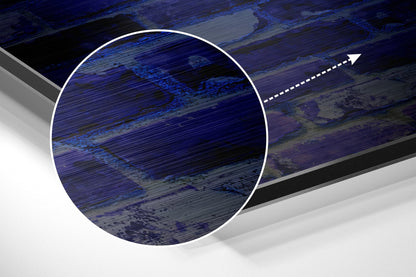 Close-up detail of brushed aluminium wall art showing blue and grey horizontal streaked texture with magnified circular view and directional arrow.