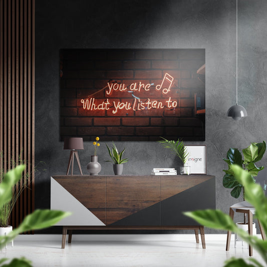 Modern living room with neon sign reading "you are what you listen to" mounted above wooden console table with plants and decor.