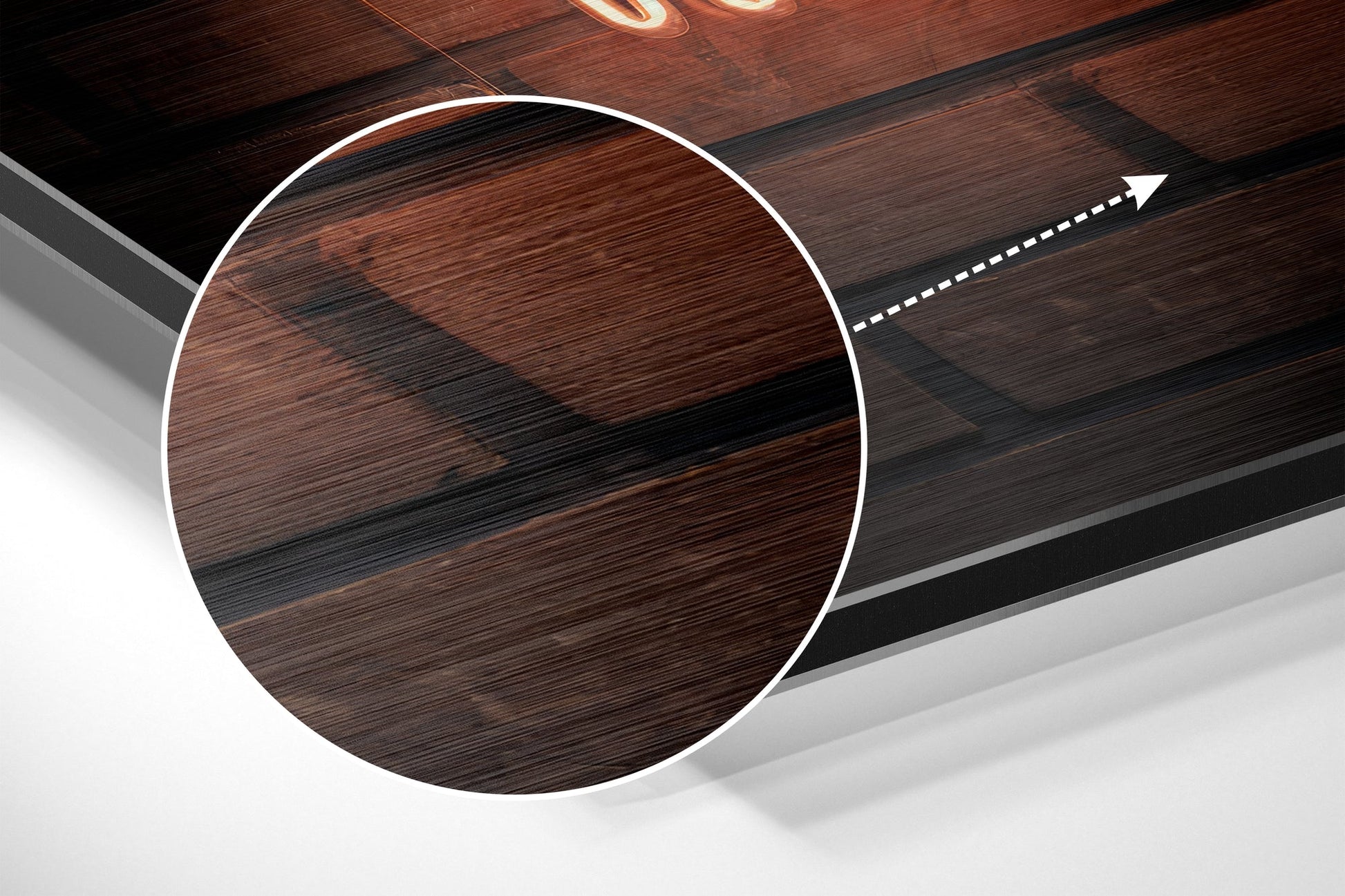 Close-up angled view of circular brushed aluminium Dibond wall art with wood grain texture in brown and black tones, white border outline, and directional arrow graphic.
