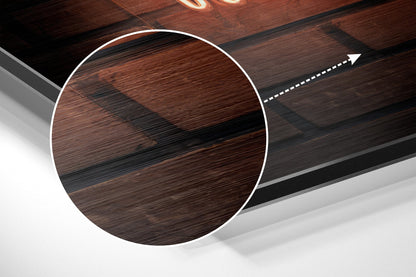 Close-up angled view of circular brushed aluminium Dibond wall art with wood grain texture in brown and black tones, white border outline, and directional arrow graphic.