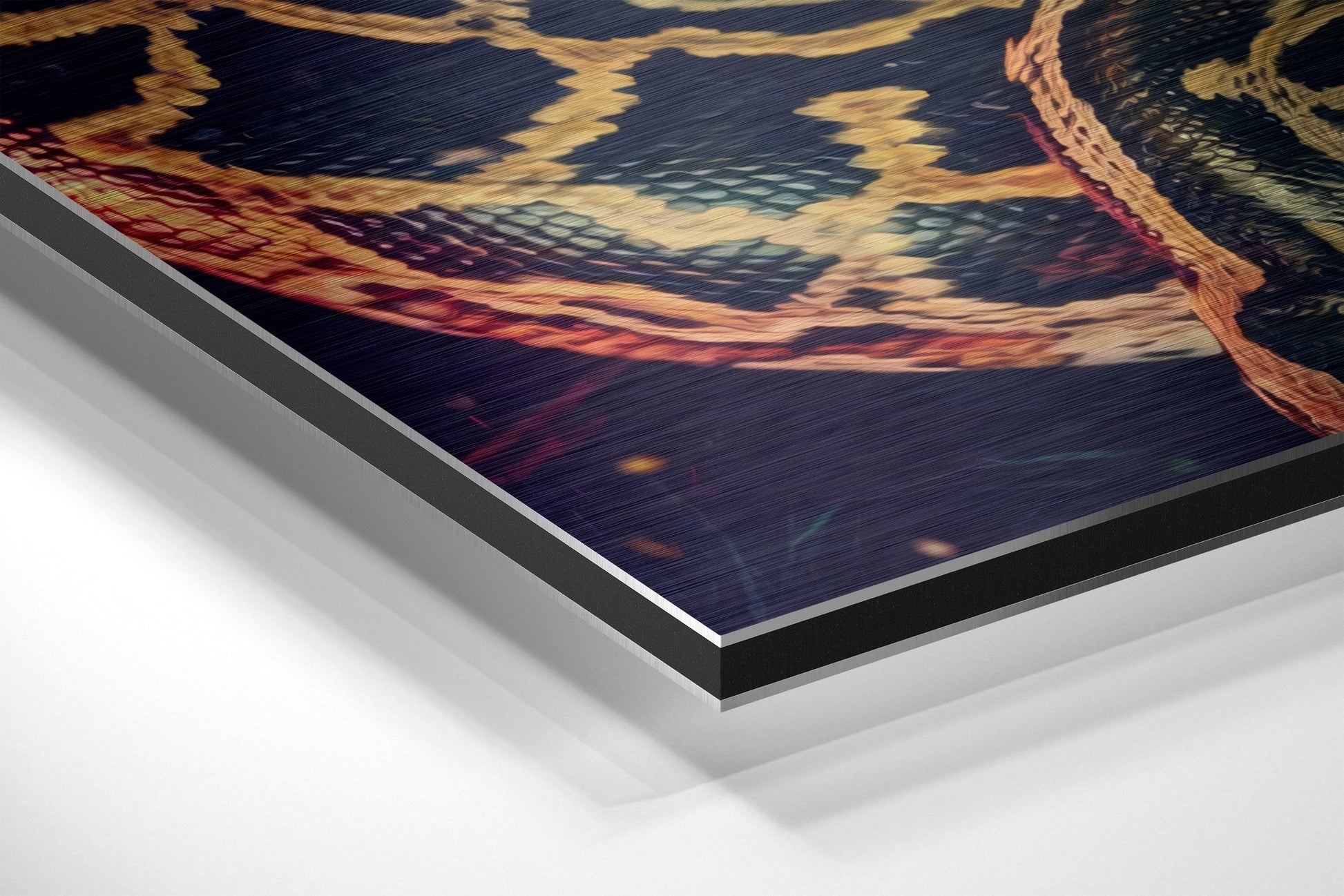 Close-up angled view of brushed aluminium Dibond panel edge showing layered construction with dark, cream, and burgundy tones depicting a sunset landscape.