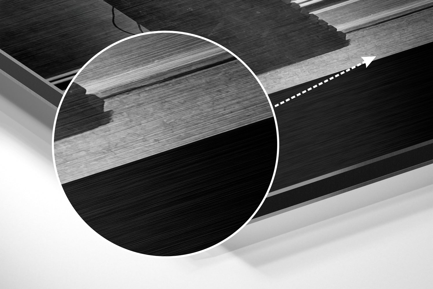 Close-up detail of brushed aluminium wall art showing layered black and grey metallic surface with horizontal texture and white circular overlay.