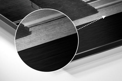 Close-up detail of brushed aluminium wall art showing layered black and grey metallic surface with horizontal texture and white circular overlay.