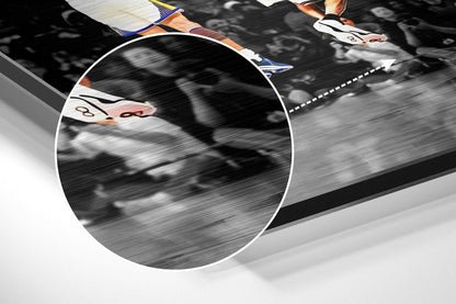 Close-up detail of brushed aluminum wall art showing athlete's feet in colored sneakers with motion blur and white dashed line on dark background.