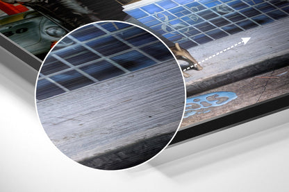 Close-up detail of brushed aluminium surface showing horizontal grain texture and blue solar panel grid pattern in background.