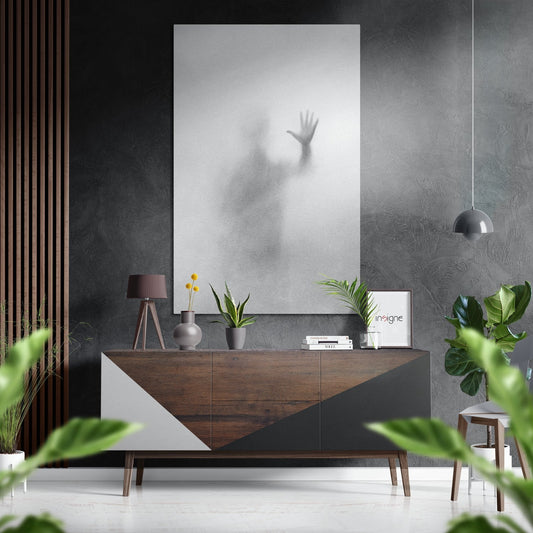 Modern interior setting with blurred silhouette palm wall art displayed above wooden dresser with plants and accessories.