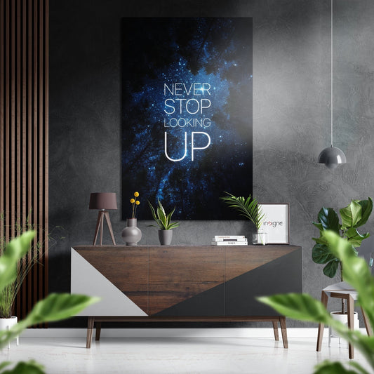 Modern interior featuring dark wood sideboard with white geometric panels displaying blue nebula wall art with "Never Stop Looking Up" text above potted plants and decorative items.