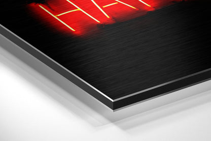 Angled perspective view of brushed black aluminum dibond panel with red neon lighting at top edge against white background.