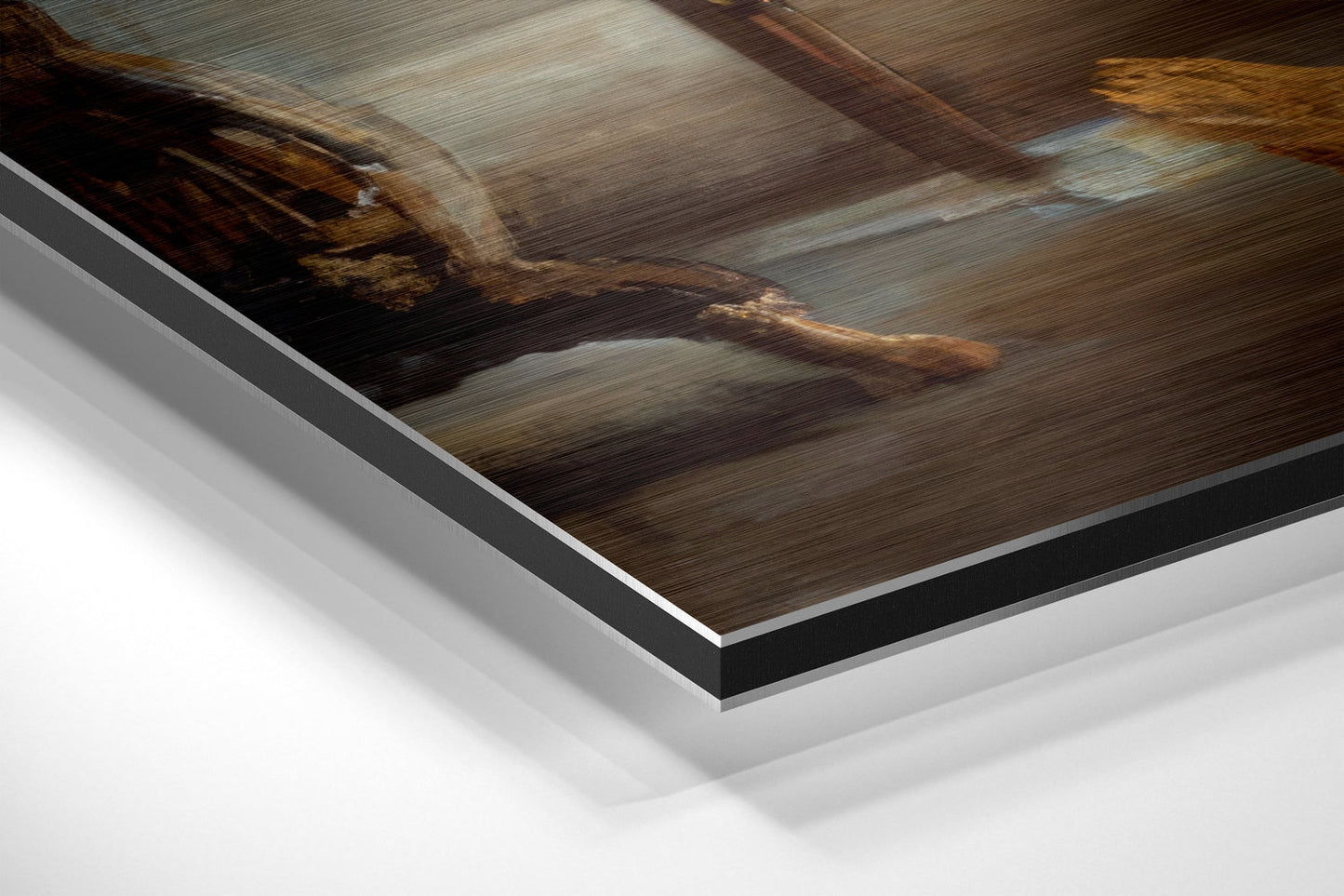 Close-up angled view of brushed aluminum Dibond print layers showing metallic silver and black edges with blurred brown wooden interior photograph.