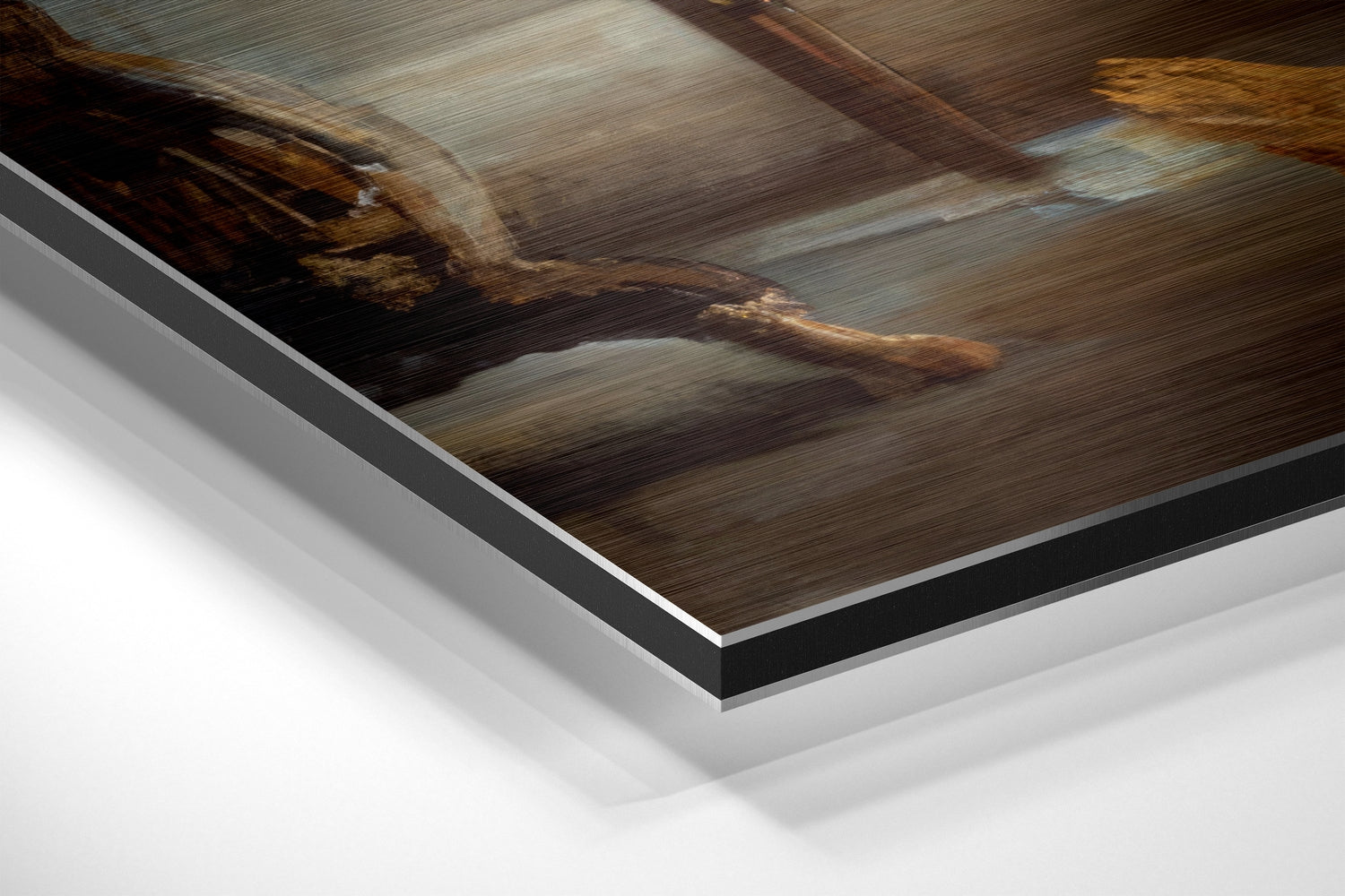 Close-up angled view of brushed aluminum Dibond print layers showing metallic silver and black edges with blurred brown wooden interior photograph.