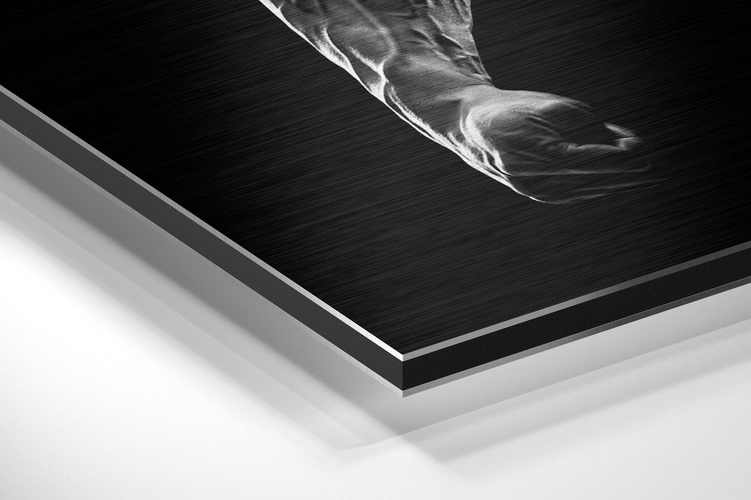 Close-up angled view of layered brushed aluminum and white mounting board edges of black and white motivational wall art.