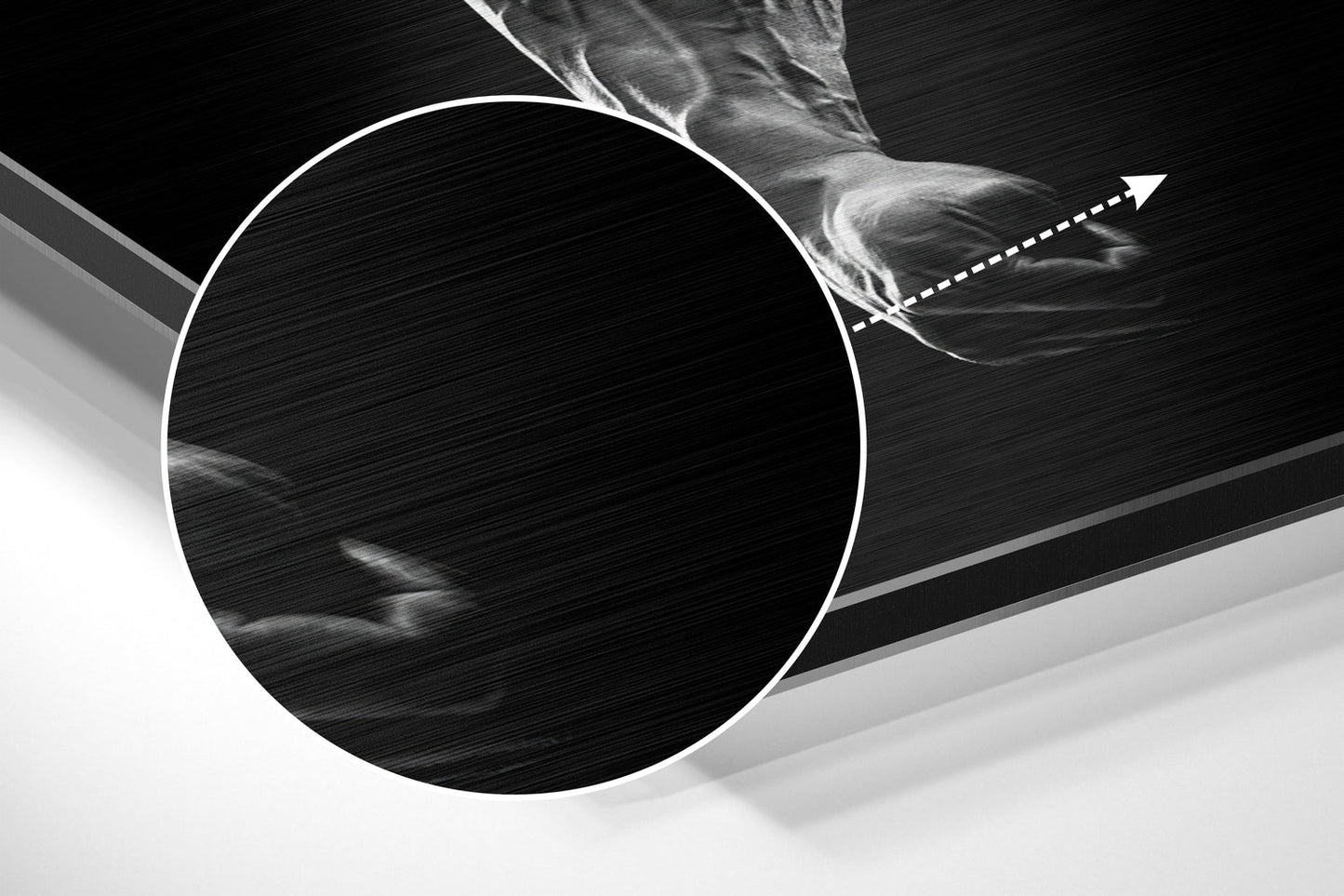 Close-up angled view of brushed aluminum wall art showing circular design with white outline and directional arrow detail against black and gray background.