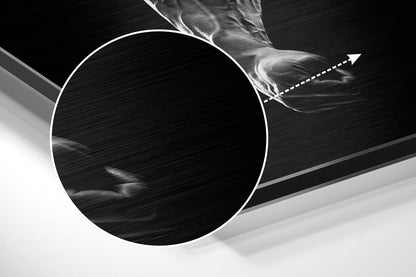 Close-up angled view of brushed aluminum wall art showing circular design with white outline and directional arrow detail against black and gray background.