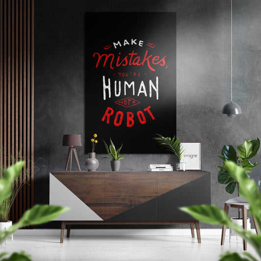 Modern living room interior with black brushed aluminium wall art displaying red and white typography quote above wooden sideboard with plants and accessories.