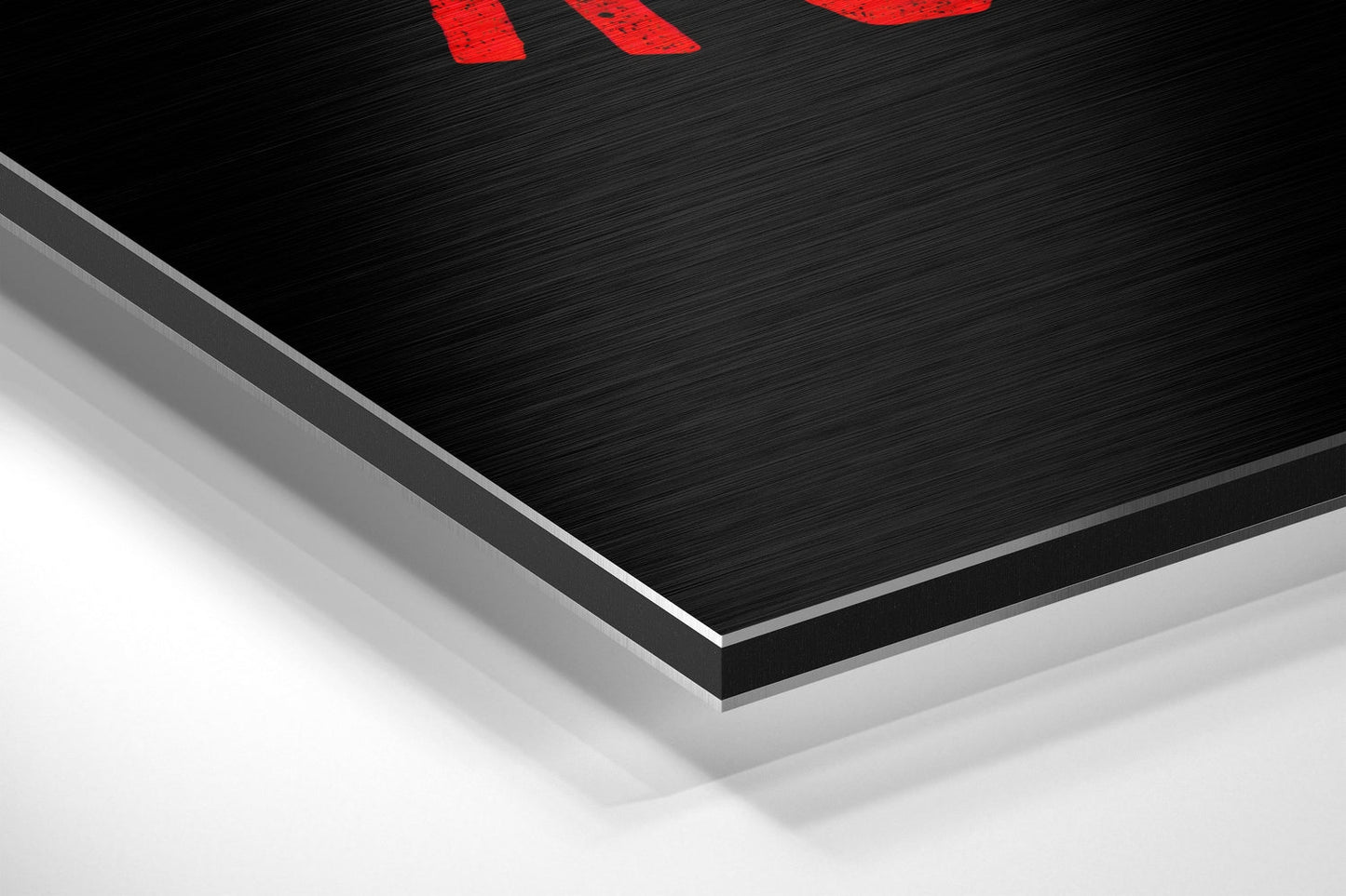 Close-up angled view of layered brushed aluminum and white composite materials showing the edge construction of the black Dibond panel with red text visible at top.