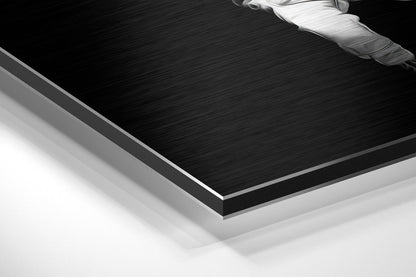 Angled side view of black brushed aluminium Dibond panel with white feather design in upper right corner, showing layered edge construction.