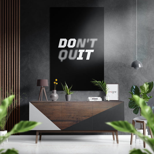 Modern interior setting featuring "DON'T QUIT" motivational text on black brushed aluminium wall art above wooden console table.