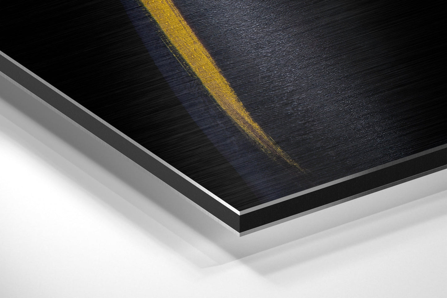 Close-up angled view of layered yellow and black brushed aluminum Dibond panel with gray edge detail against white background.