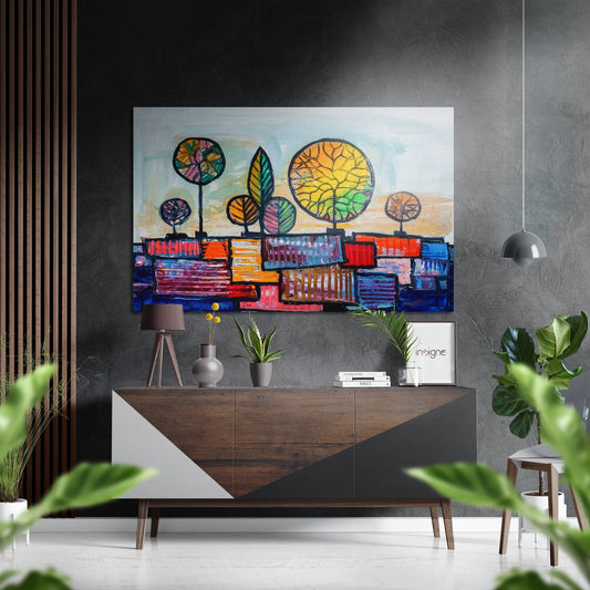 Colorful abstract wall art with stylized trees and geometric cityscape displayed above a wooden mid-century console in a modern interior setting.