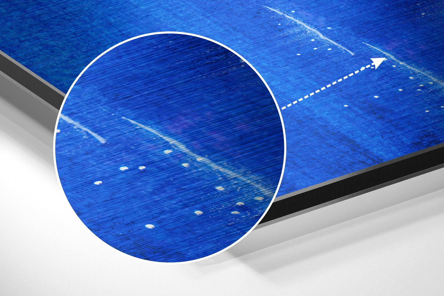 Angled close-up of brushed aluminium Dibond wall art featuring blue textured surface with white magnified circle detail and directional arrow.
