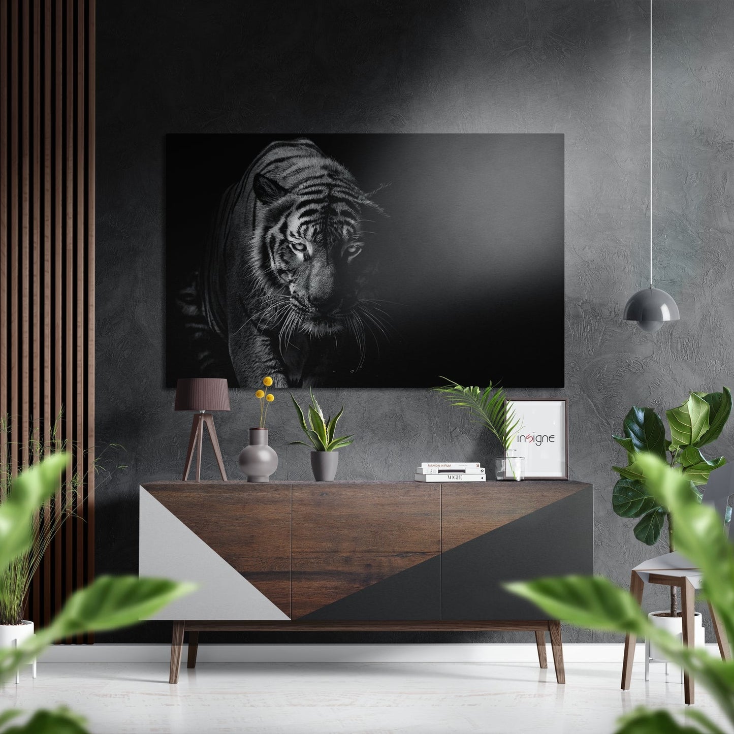 Black and white tiger portrait mounted on grey wall above wooden dresser with plants and decorative items in modern interior setting.