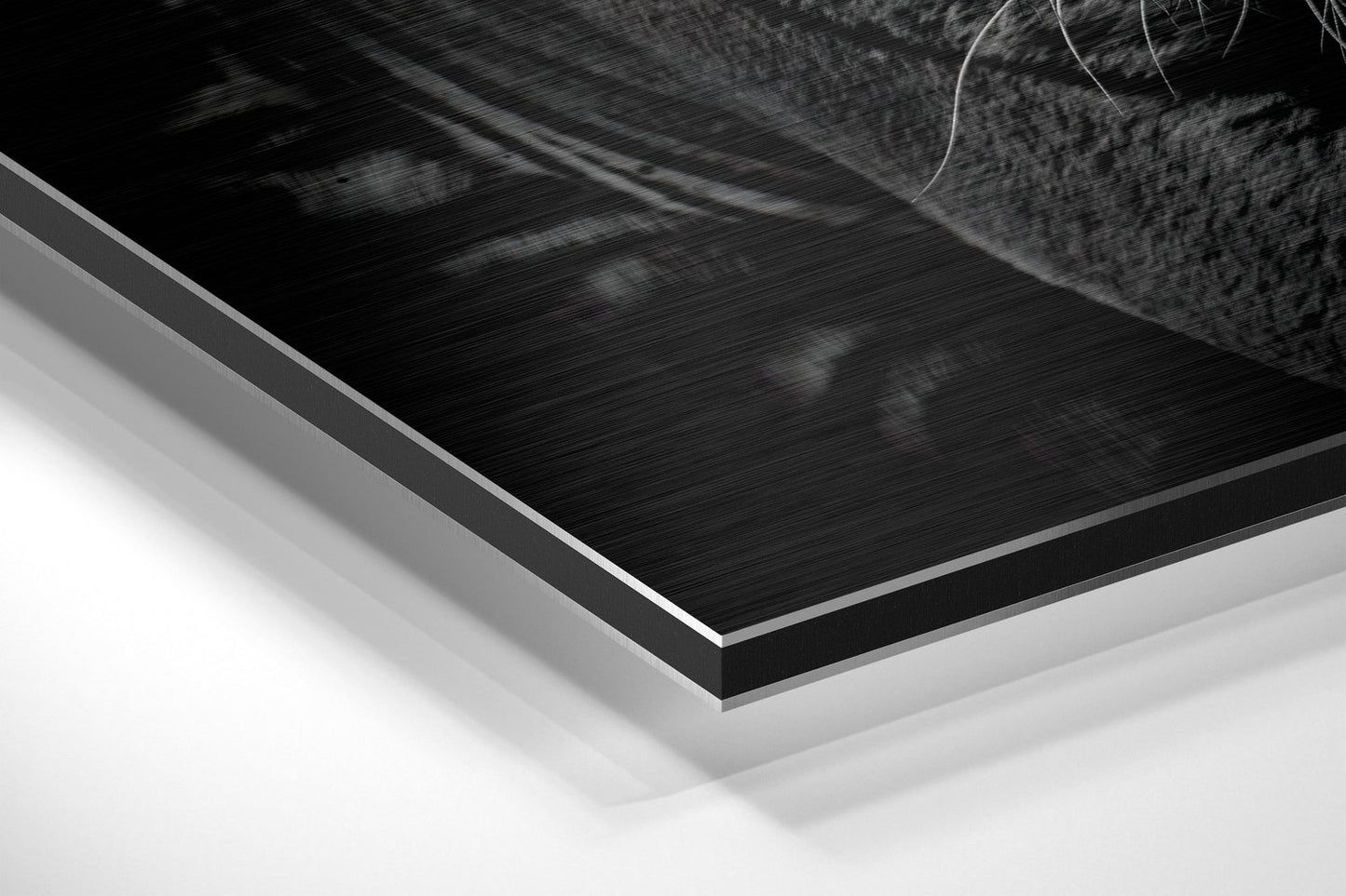 Close-up angled view of layered Dibond wall art showing brushed black aluminum surface with white backing layers.