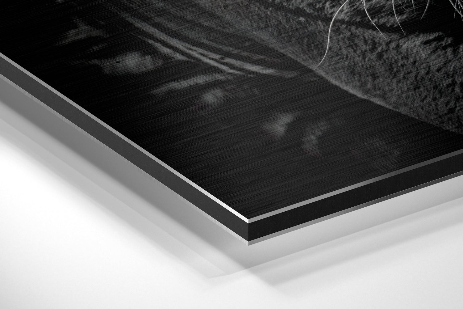 Close-up angled view of layered Dibond wall art showing brushed black aluminum surface with white backing layers.