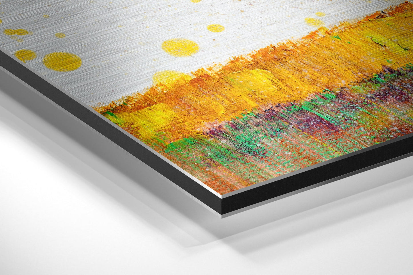 Close-up angled view of brushed aluminum dibond print edge showing layered construction with yellow, orange, green and red painted tree artwork visible on surface.