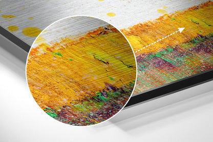 Close-up detail of brushed aluminium surface showing yellow, orange, green, and red textured finish with horizontal grain pattern and magnified circular section.