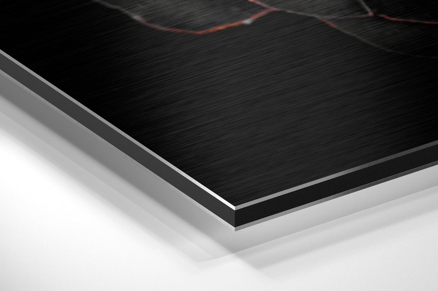 Close-up angled view of layered Dibond panel showing brushed black aluminum surface with silver edge and white backing layer.