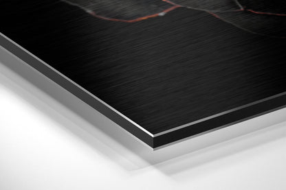 Close-up angled view of layered Dibond panel showing brushed black aluminum surface with silver edge and white backing layer.