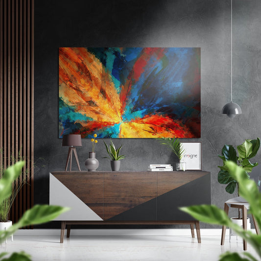 Colorful abstract flower artwork with radiating orange, yellow, blue, and red brushstrokes displayed above a wooden credenza in a modern interior.