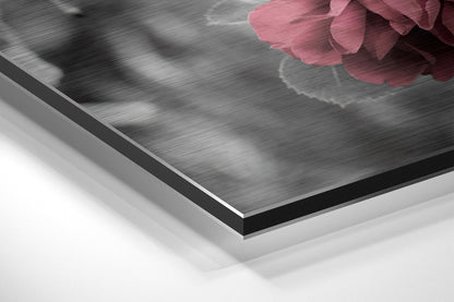 Close-up angled view of layered brushed aluminum and white composite materials with pink rose petals visible at top edge.