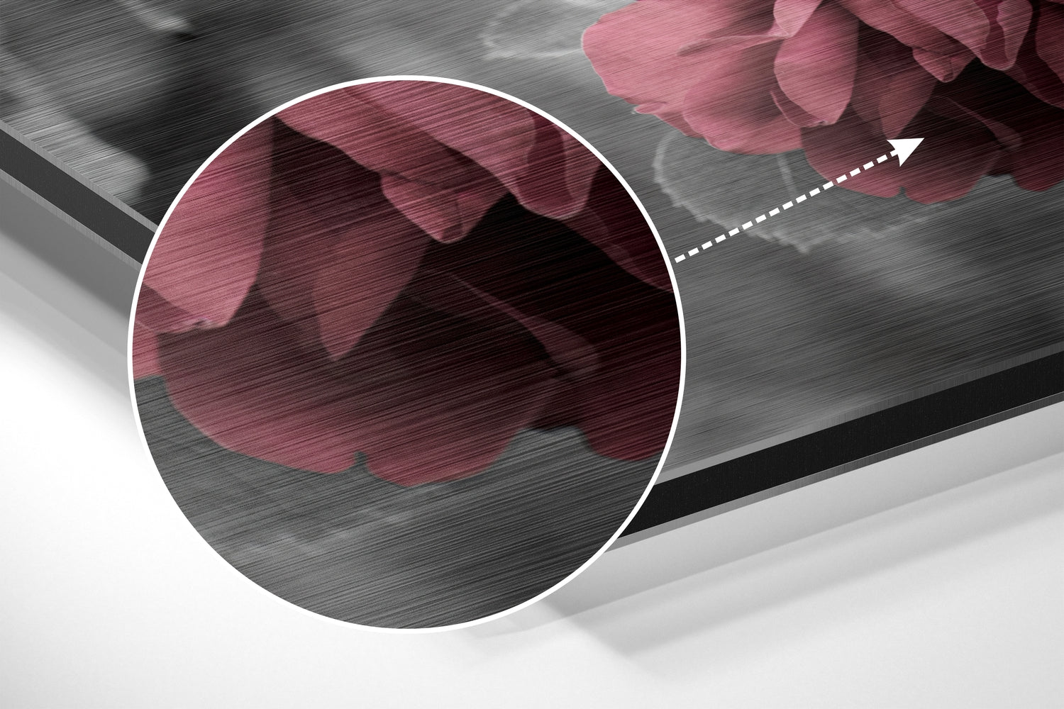 Close-up detail of brushed aluminium surface with pink rose petals and magnified circular view showing texture.