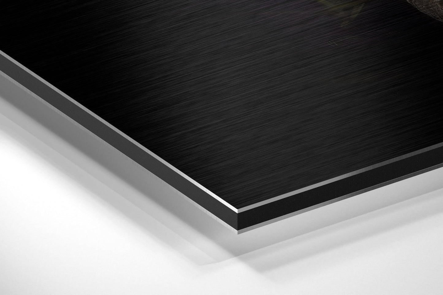 Close-up angled view of layered Black Swan Dibond panel showing brushed black aluminum surface with white foam core edge visible.
