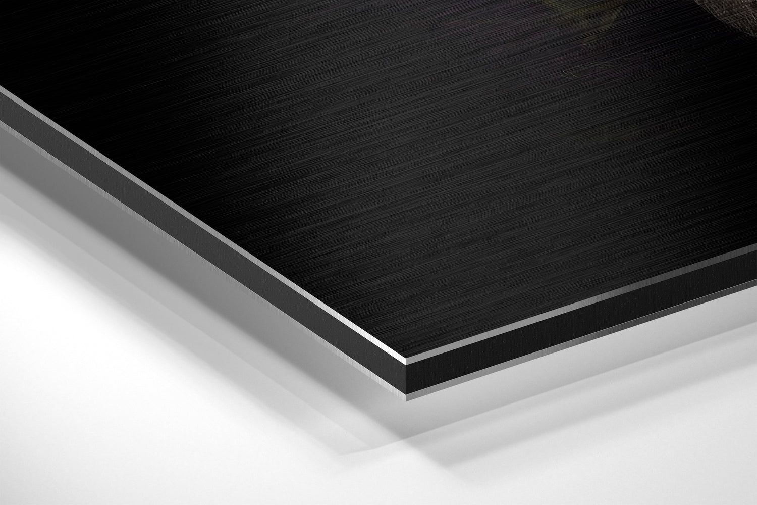 Close-up angled view of layered Black Swan Dibond panel showing brushed black aluminum surface with white foam core edge visible.